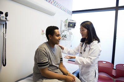 A doctor and a teenage boy chat in an exam room at the Adolescent Health Center at Children's National Hospital.